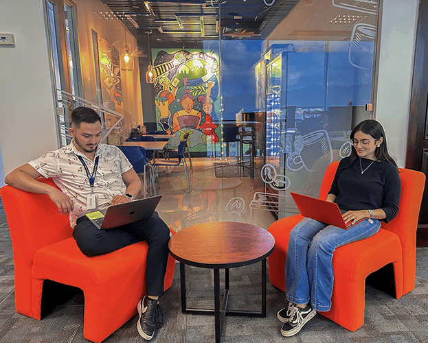 two coworkers with their laptops at the office